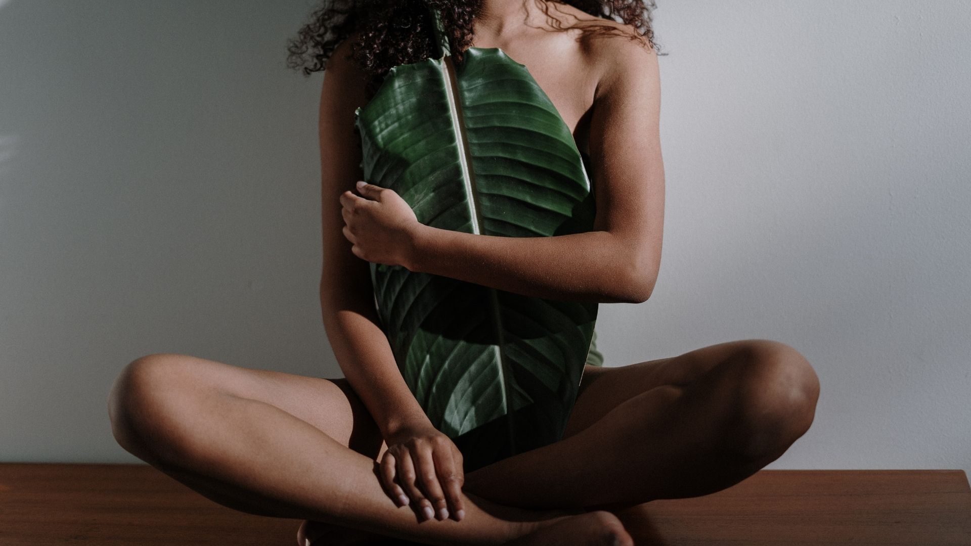 Woman sitting cross legged with a leaf.